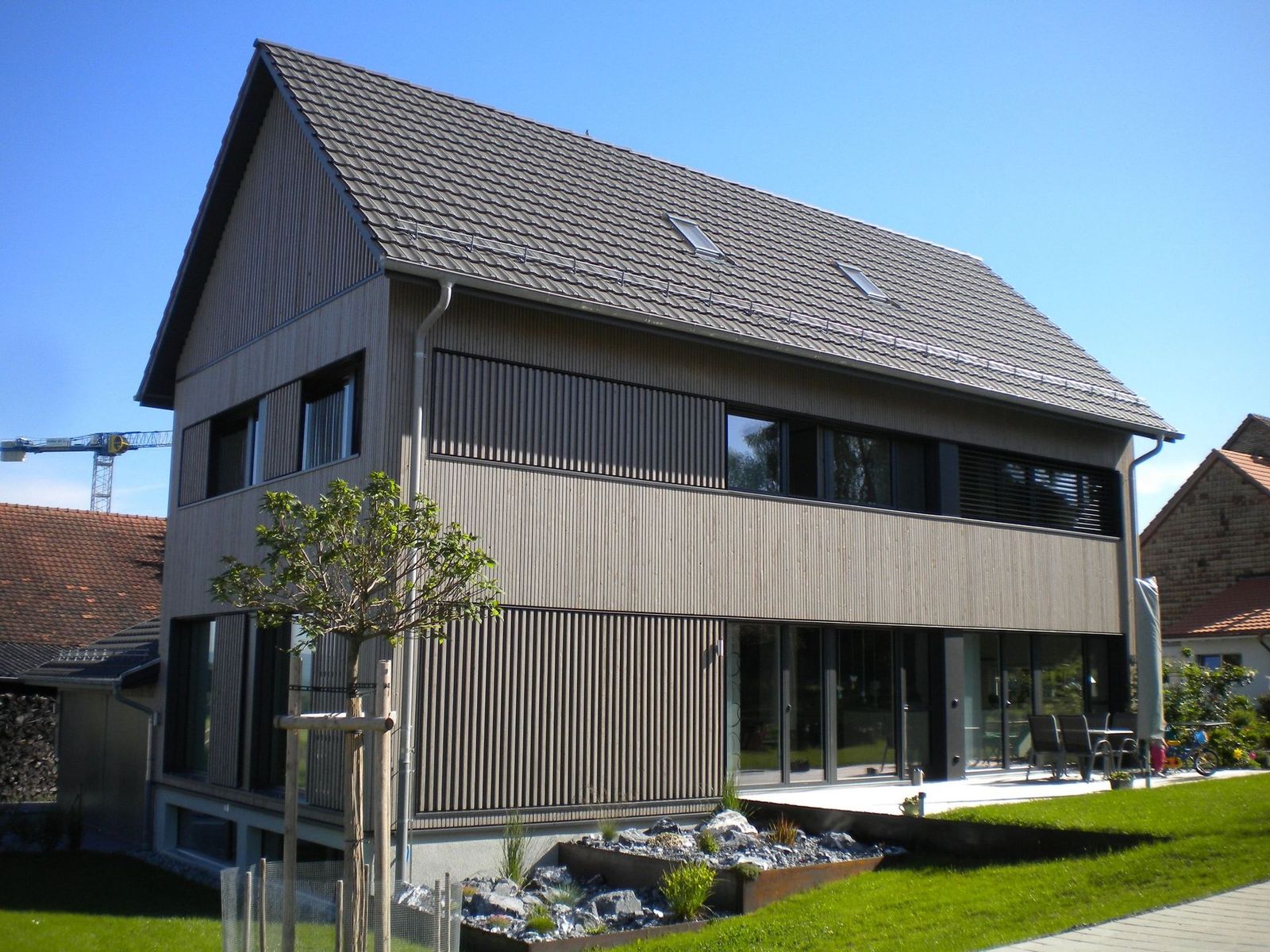 Wohnhaus mit dunkler Fassadenverkleidung und Dachaufbau.